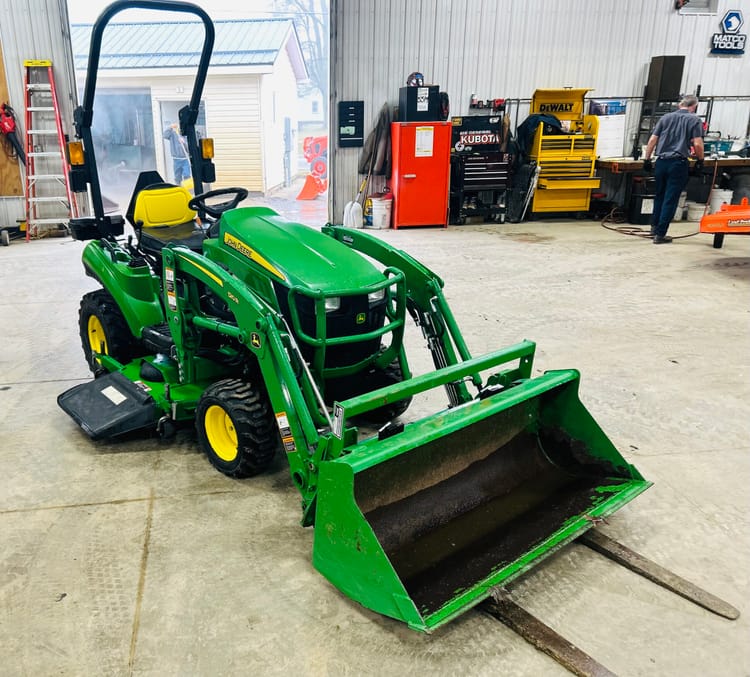 SUPER NICE LOW HOUR JOHN DEERE 1023E w/60″ MOWER , 54″ BUCKET & 36″ PALLET FORKS